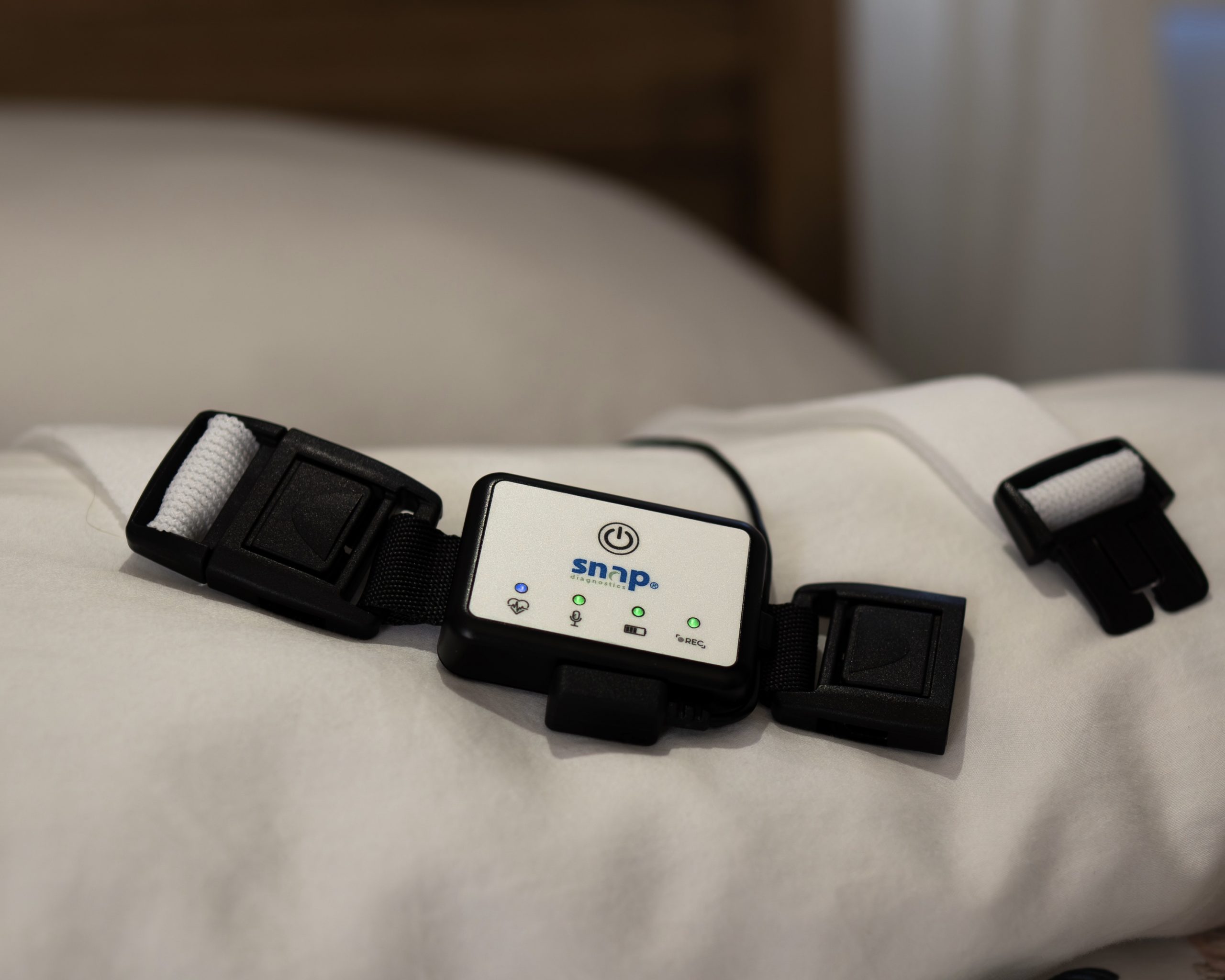 A small home sleep apnea test kit with a nasal cannula and finger sensor laid neatly on a bedside table next to a lamp